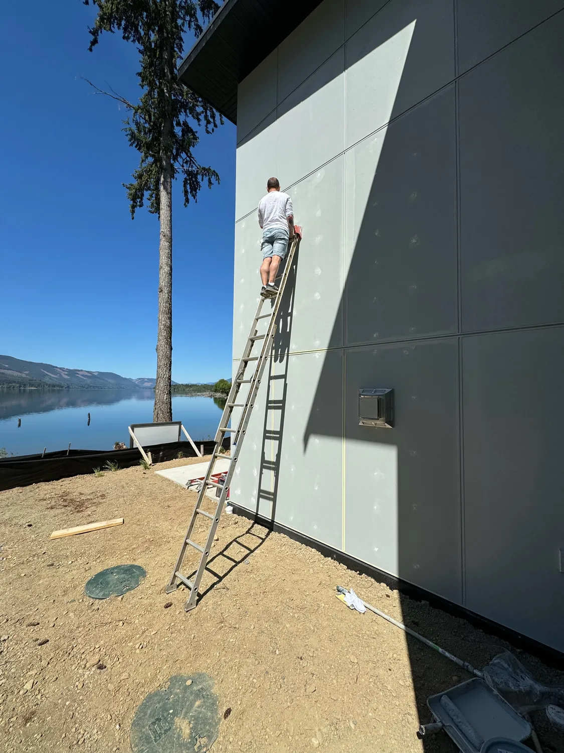 Painter working from a ladder on the exterior wall of a home